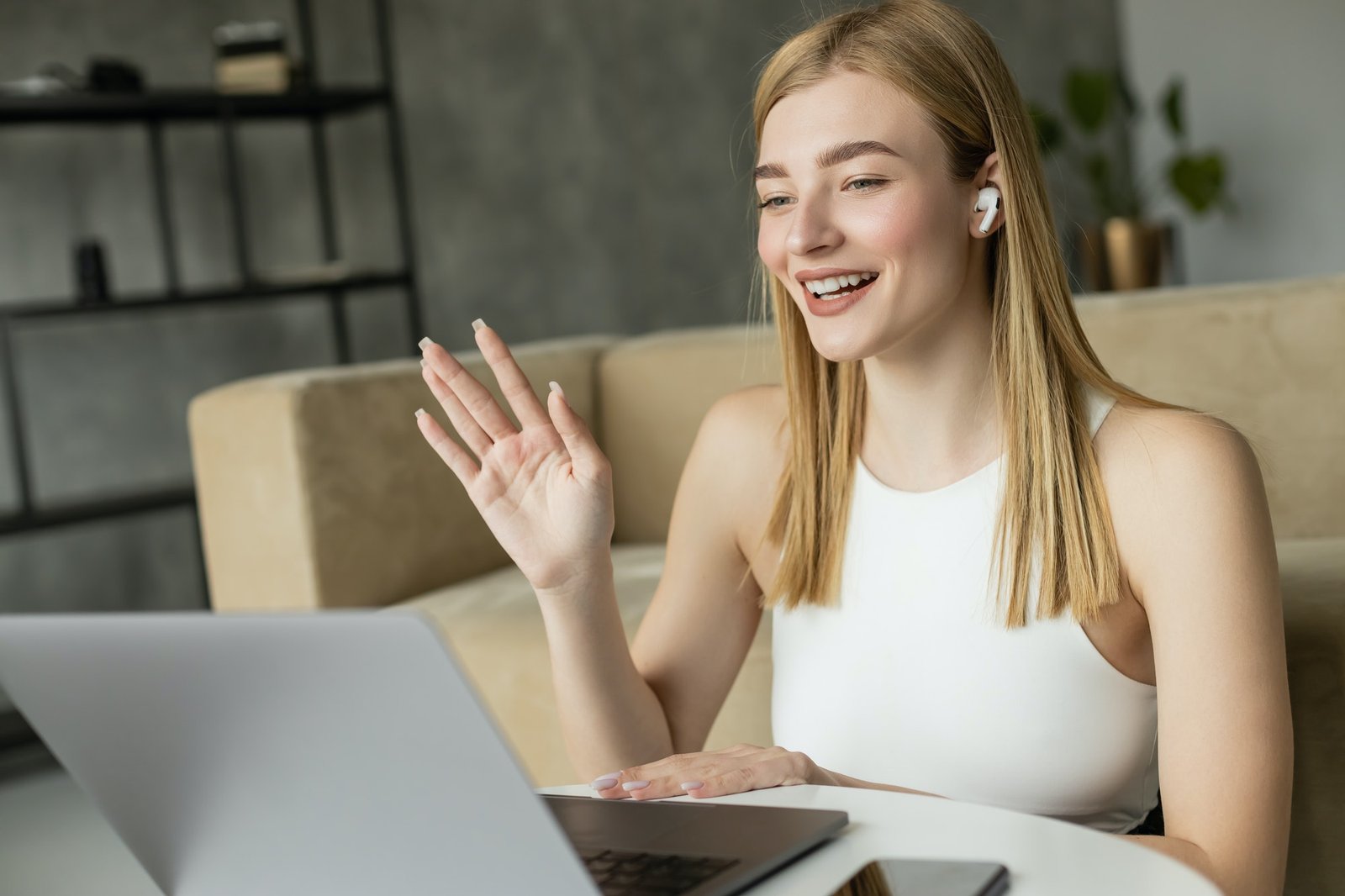 Smiling blonde coach in earphone having video call on laptop at home